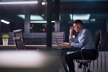 Image showing man working on laptop in dark office