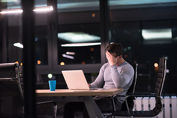 Image showing man working on laptop in dark office