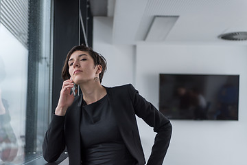 Image showing Elegant Woman Using Mobile Phone by window in office building