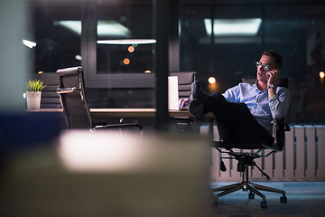 Image showing businessman using mobile phone in dark office