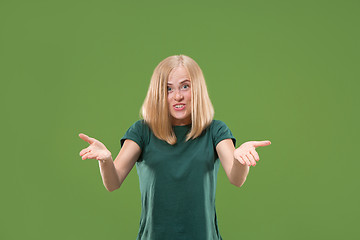 Image showing Beautiful female half-length portrait isolated on green studio backgroud. The young emotional surprised woman