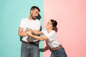 Image showing young couple watching tv and fighting to get the remote control