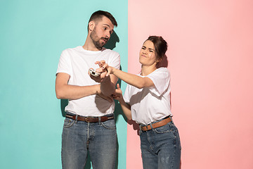 Image showing young couple watching tv and fighting to get the remote control