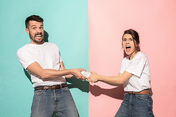 Image showing young couple watching tv and fighting to get the remote control