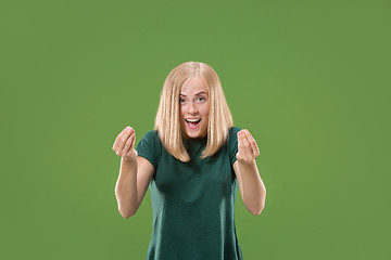 Image showing Beautiful female half-length portrait isolated on green studio backgroud. The young emotional surprised woman