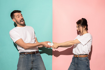 Image showing young couple watching tv and fighting to get the remote control