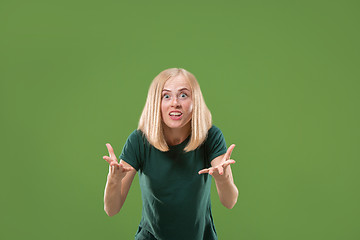 Image showing Beautiful female half-length portrait isolated on green studio backgroud. The young emotional surprised woman