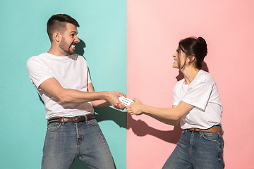 Image showing young couple watching tv and fighting to get the remote control