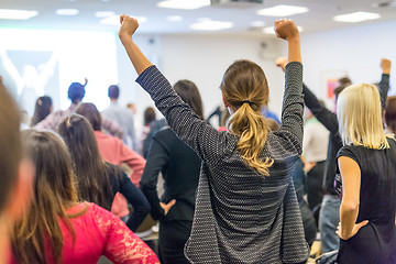 Image showing Participants of interactive motivational speech feeling empowered and motivated, hands raised high in the air.