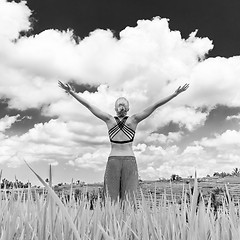 Image showing Relaxed healthy sporty woman, arms rised to the sky, enjoying pure nature at beautiful green rice fields on Bali.