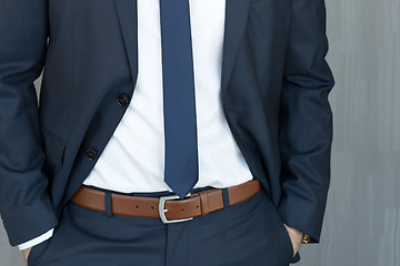 Image showing Torso of a businessman standing with hands clenched in middle position in a classic navy blue suit.