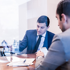 Image showing Two young businessmen using electronic devices at business meeting.