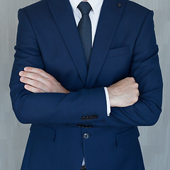 Image showing Torso of anonymous businessman standing with hands in lowered steeple wearing beautiful fashionable classic grey suit, white shirt and blue tie.