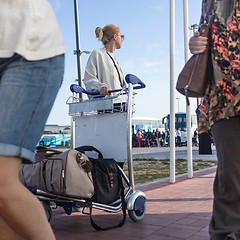 Image showing Young woman transporting luggage from arrival parking to international airport departure termainal by luggage trolley.