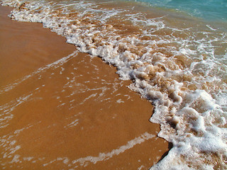 Image showing Sea wave with white foam on the sandy beach