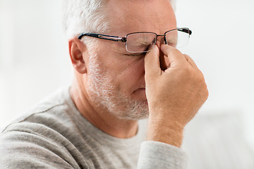 Image showing senior man in glasses massaging nose bridge