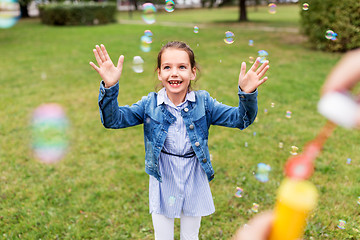 Image showing happy girl playing with soap bubbles at park