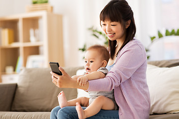 Image showing asian mother with baby son taking selfie at home