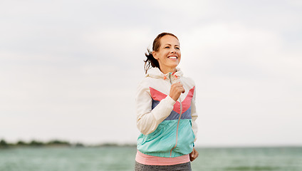 Image showing smiling woman running along beach