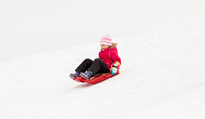 Image showing happy little girl sliding down on sled in winter