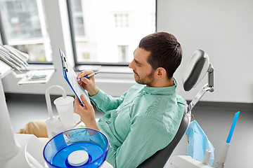 Image showing patient filling application form at dental clinic