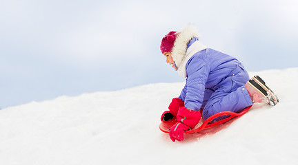 Image showing girl sliding down on snow saucer sled in winter