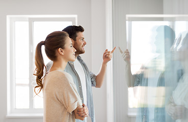 Image showing happy couple looking through window at new home