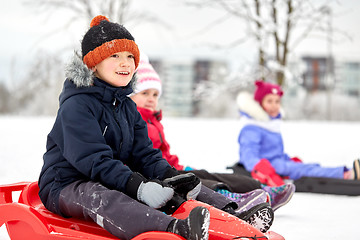 Image showing happy kids sliding on sleds in winter