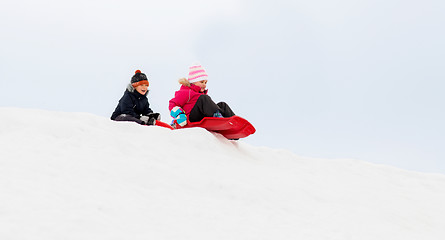 Image showing happy kids sliding on sleds down hill in winter