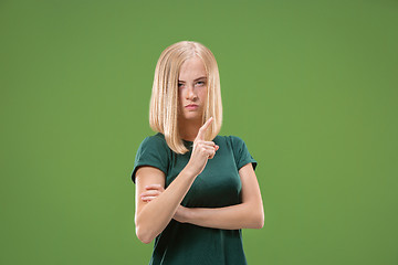 Image showing Suspiciont. Doubtful pensive woman with thoughtful expression making choice against green background