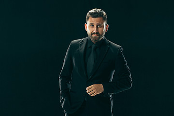 Image showing Male beauty concept. Portrait of a fashionable young man with stylish haircut wearing trendy suit posing over black background.