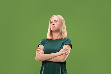 Image showing Suspiciont. Doubtful pensive woman with thoughtful expression making choice against green background