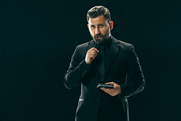 Image showing Male beauty concept. Portrait of a fashionable young man with stylish haircut wearing trendy suit posing over black background.