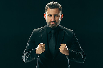 Image showing Male beauty concept. Portrait of a fashionable young man with stylish haircut wearing trendy suit posing over black background.