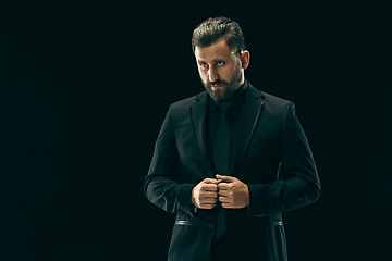 Image showing Male beauty concept. Portrait of a fashionable young man with stylish haircut wearing trendy suit posing over black background.