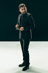 Image showing Male beauty concept. Portrait of a fashionable young man with stylish haircut wearing trendy suit posing over black background.