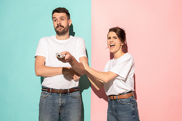 Image showing young couple watching tv and fighting to get the remote control