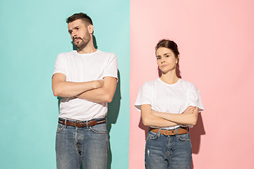 Image showing The serious man and woman looking at camera against pink and blu