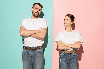 Image showing The serious man and woman looking at camera against pink and blu