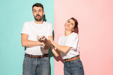 Image showing young couple watching tv and fighting to get the remote control