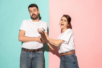 Image showing young couple watching tv and fighting to get the remote control