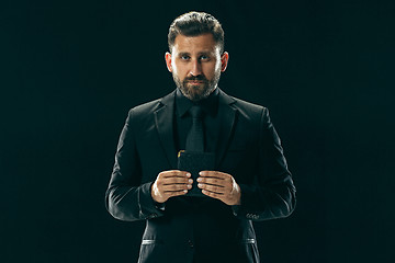 Image showing Male beauty concept. Portrait of a fashionable young man with stylish haircut wearing trendy suit posing over black background.