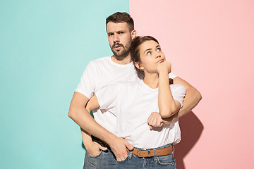 Image showing Let me think. Doubtful pensive couple with thoughtful expression making choice against pink background