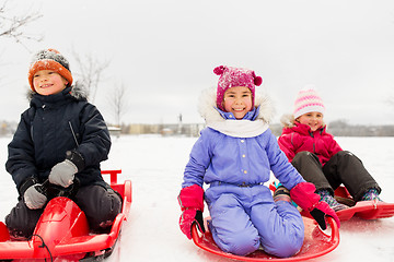 Image showing happy little kids sliding down on sleds in winter