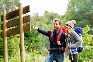 Image showing couple of travelers with backpacks at signpost