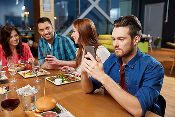 Image showing man messaging on smartphone at restaurant