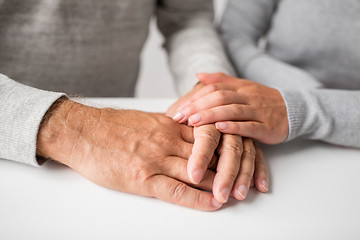 Image showing close up of young woman holding senior man hands