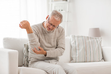 Image showing unhappy senior man suffering elbow pain at home