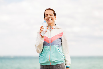 Image showing woman drinking water after exercising at seaside