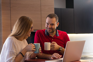 Image showing couple drinking coffee and using laptop at home